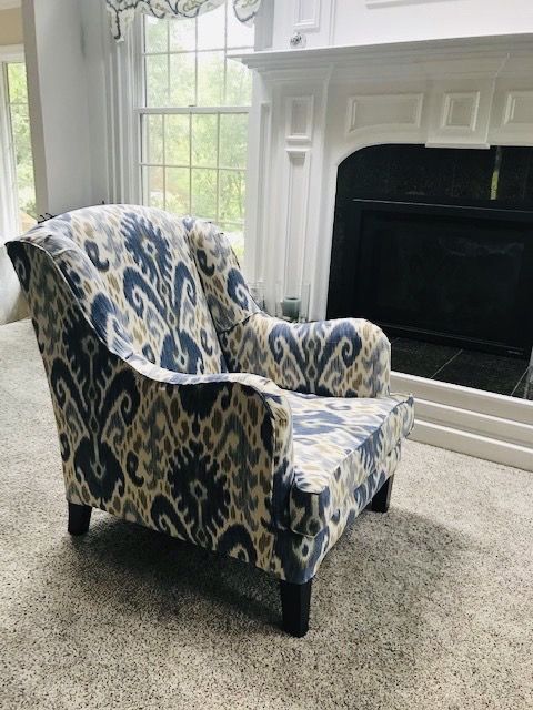 Club chair in a blue ikat loose cover beside a fireplace