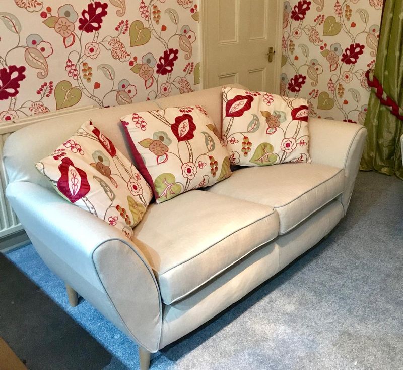 Cream sofa loose cover with red piping and floral cushions