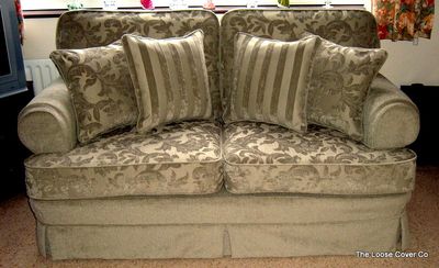 Two-seater sofa in a green damask loose cover with striped cushions