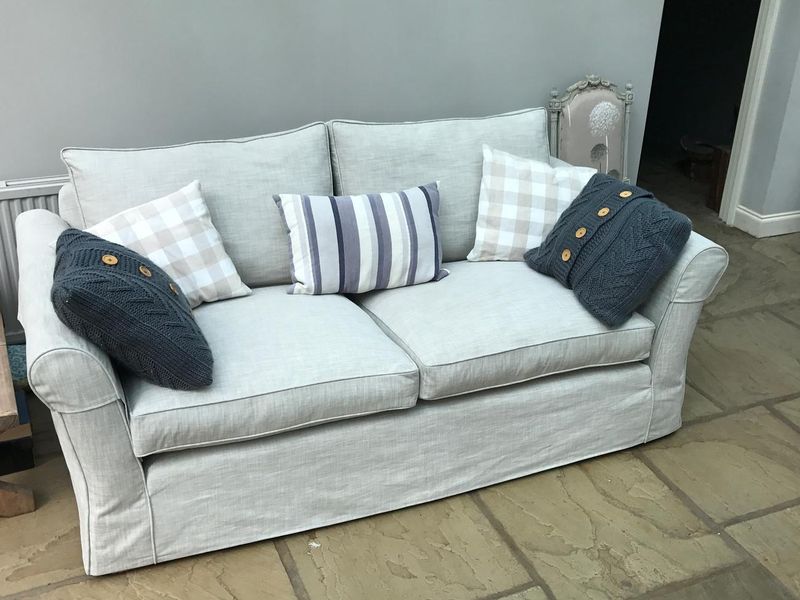 Two-seater sofa in a pale grey loose cover with check cushions