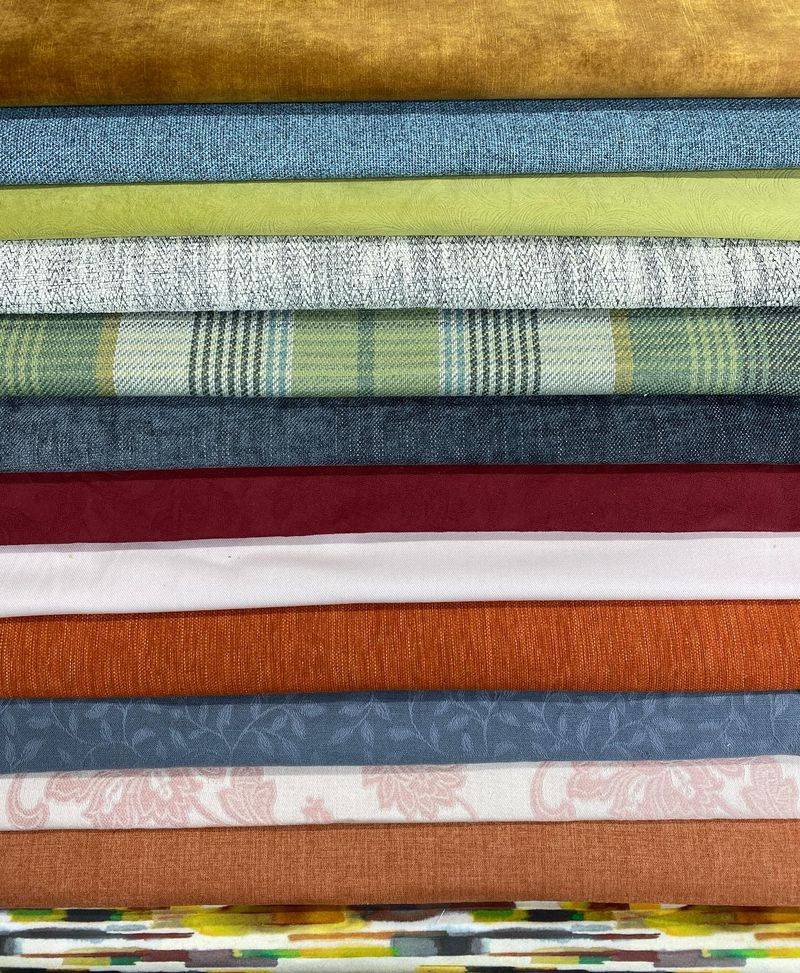 Stack of polyester loose cover fabrics in ochre, green, red, orange and blue