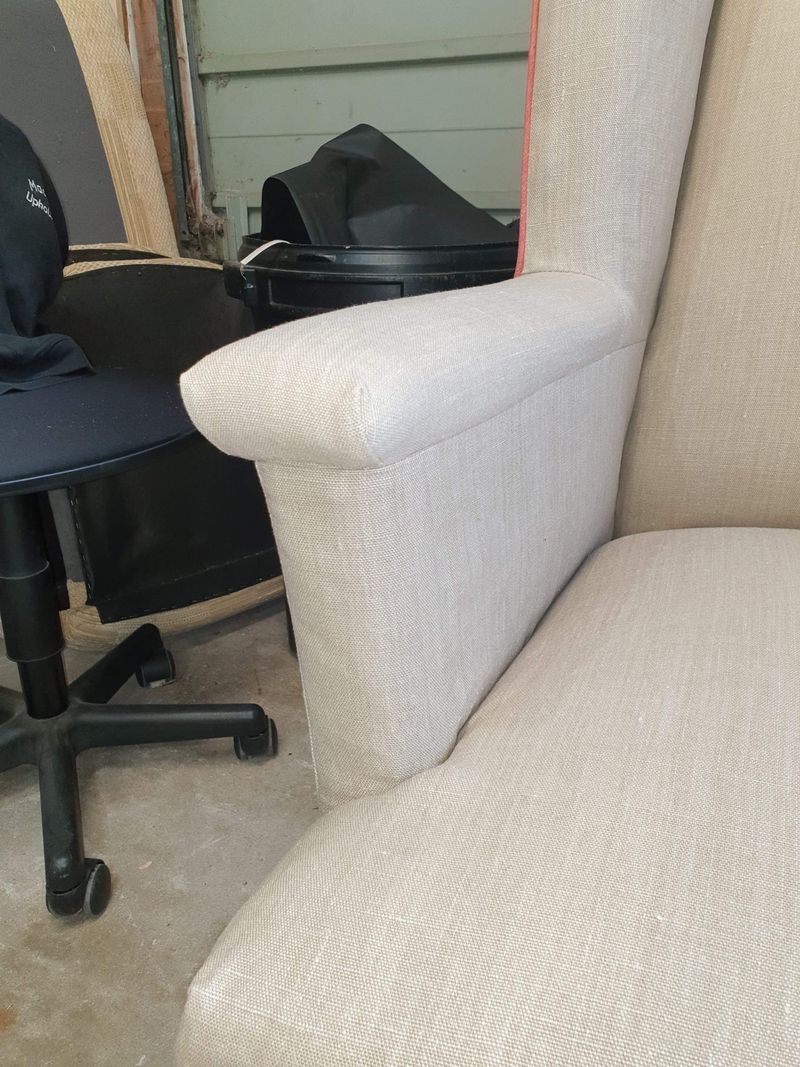 Cream slipcover on a wing chair arm, made by Raymond