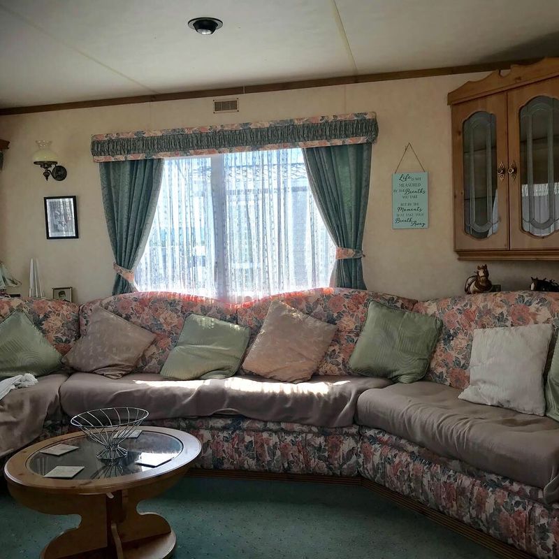 Static caravan before its makeover, with old floral seat covers and curtains