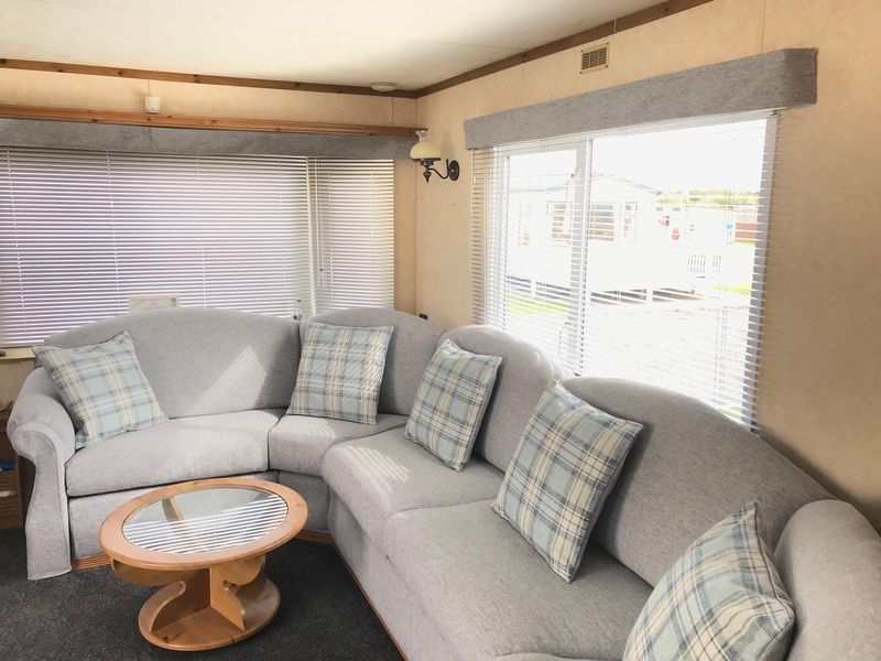 Static caravan lounge with new grey seat covers and a matching pelmet
