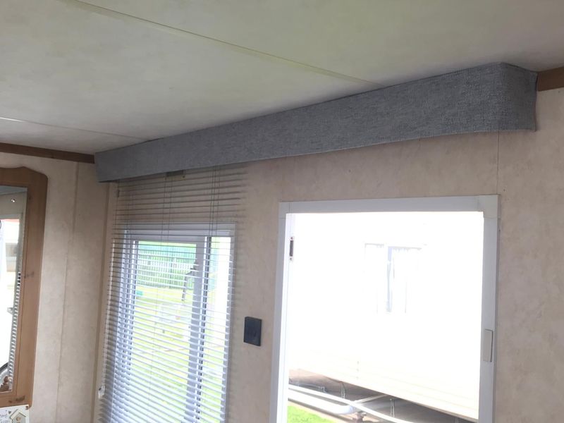 Static caravan window pelmet covered in grey fabric